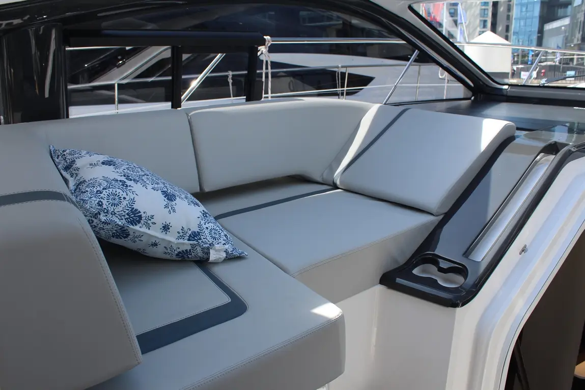A stylish grey seating area on a boat, featuring a decorative blue floral cushion and a cup holder.